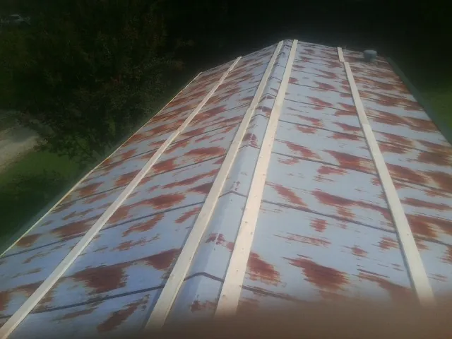Rusted metal roof panels with new wood purlins before replacement — Storm Damage Roof Repair in Cortland by Roofing Brothers