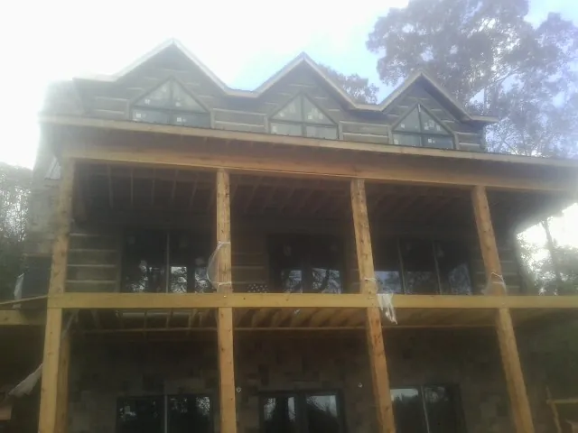 Dormers and porch framing on a large log home under construction — Roof Coating work by our crew in Cortland